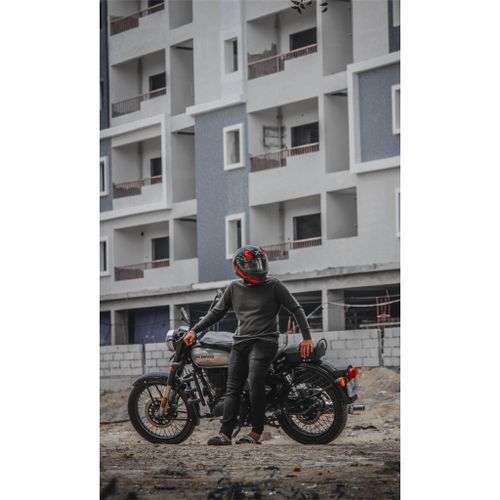 Free A motorcycle rider stands beside his bike in front of a modern apartment building in Hyderabad, India. Stock Photo