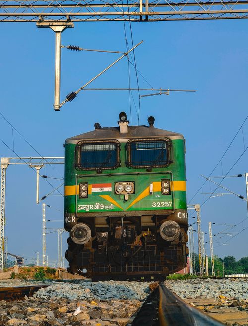 Free Green Indian locomotive captured from a low angle on a clear day, highlighting railway infrastructure. Stock Photo