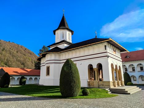 Beautiful Orthodox chapel surrounded by greenery in Transylvania with blue skies overhead.