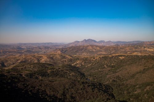 Free A stunning aerial view of rolling mountains under a cloudless blue sky, highlighting natural beauty. Stock Photo