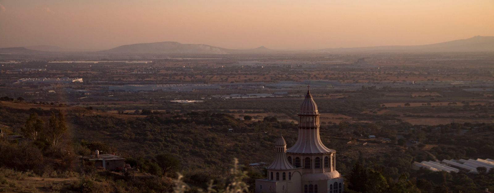 Stunning aerial view of the Santuario de los Martires with a picturesque Mexican landscape at sunset.