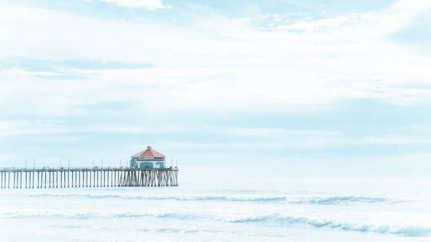 A tranquil view of Manhattan Beach Pier with gentle waves and a serene blue sky.