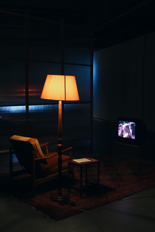 Free A warm, cozy living room featuring an armchair, illuminated lamp, and television creating an inviting ambiance. Stock Photo
