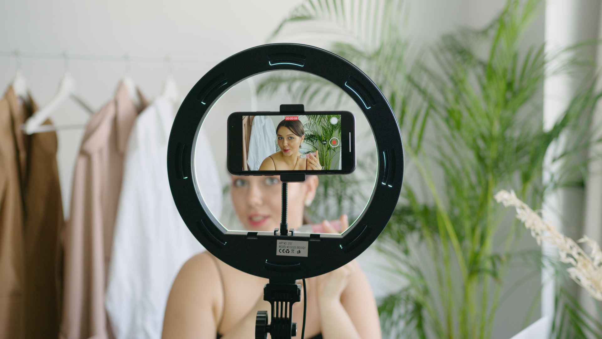 Une femme filme du contenu vidéo avec un smartphone et une lumière annulaire.