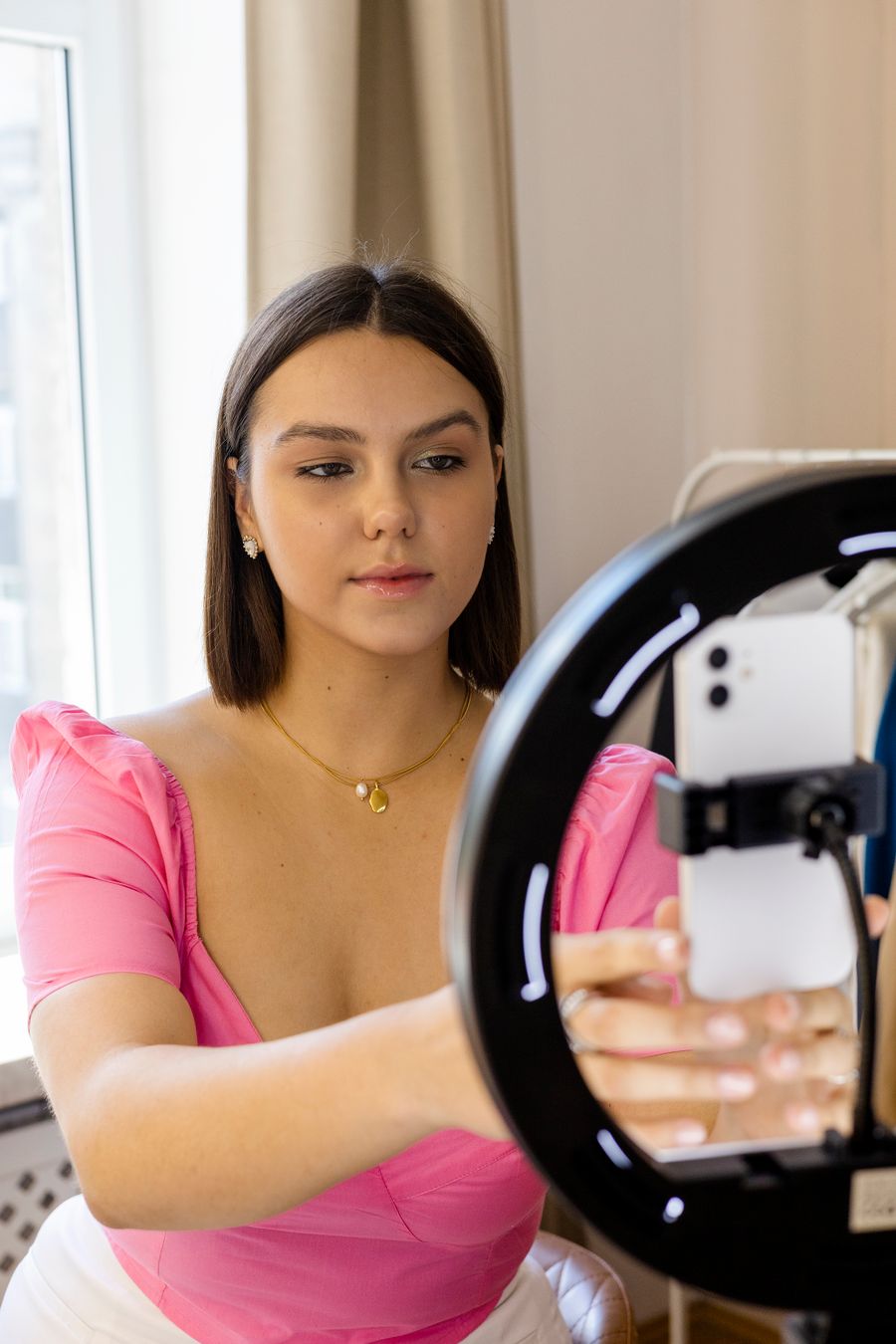 Content creator holding a phone beside a ring light to create marketing content