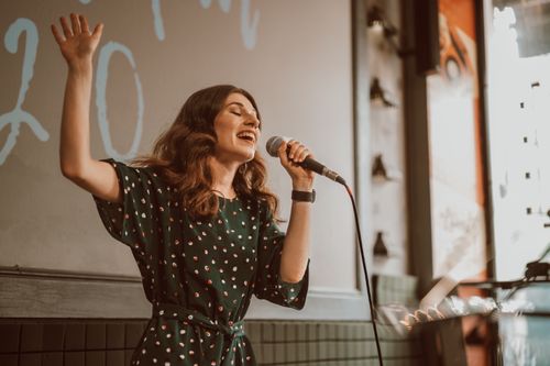 Free Female musician singing passionately with a microphone indoors. Stock Photo