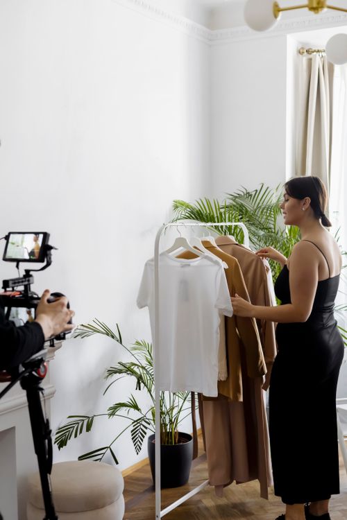 Free Woman filming a fashion vlog with clothes rack and professional camera setup. Stock Photo