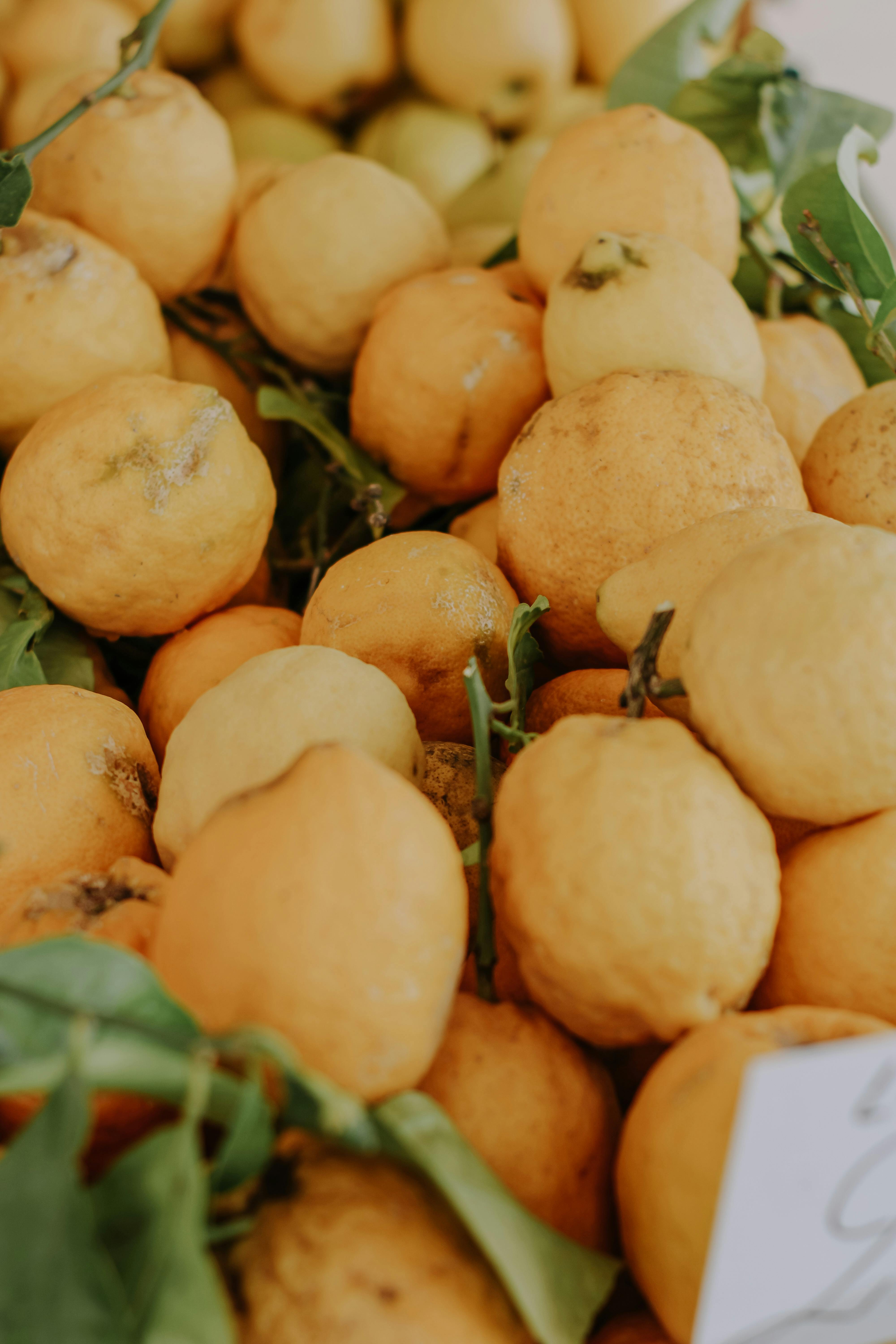 A close-up of fresh organic lemons with green leaves, showcasing vibrant yellow hues.
