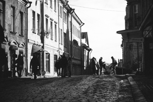 Free Classic black and white photo of a cobblestone street with people and historic buildings. Stock Photo