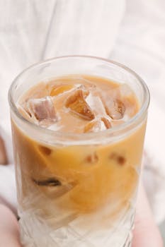 Close-up of creamy iced coffee with ice cubes in a clear glass, perfect for a cool refreshment.
