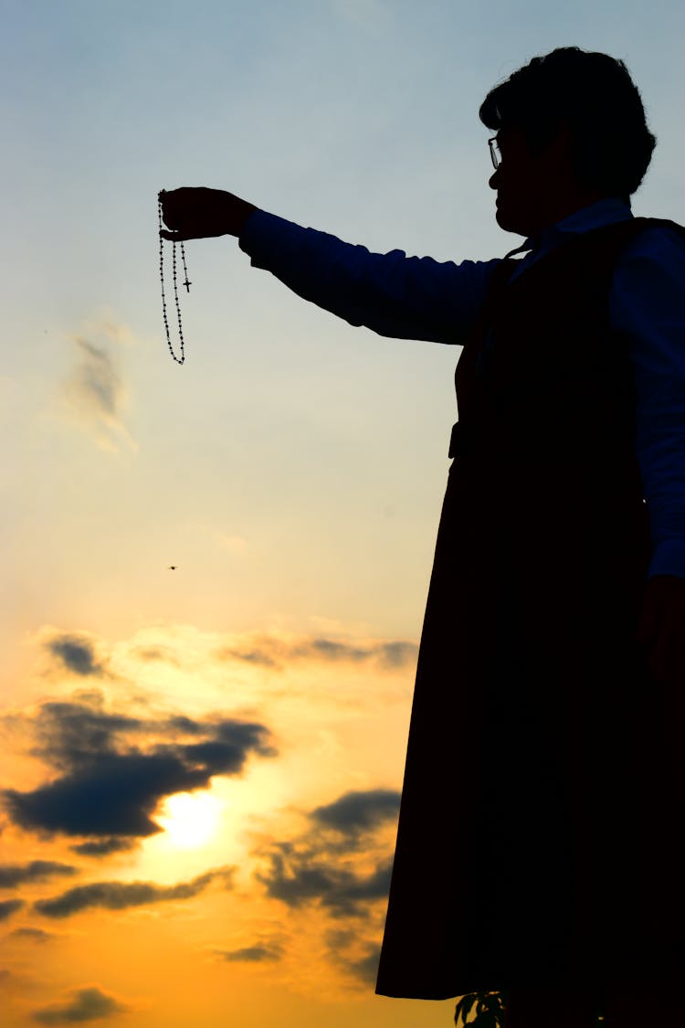 Silhouette Of A Person Holding A Rosary