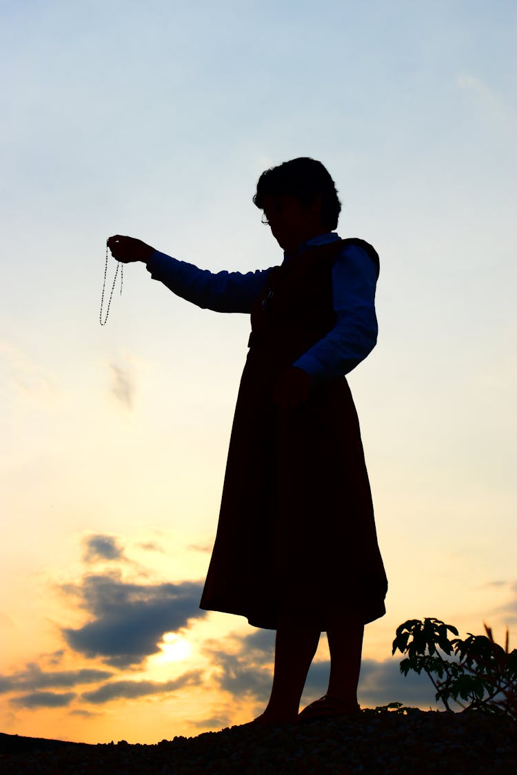 Silhouette Of A Person Holding A Necklace