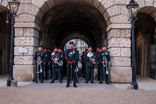 Free Marching band in military uniform performing under a historic stone archway in England. Stock Photo