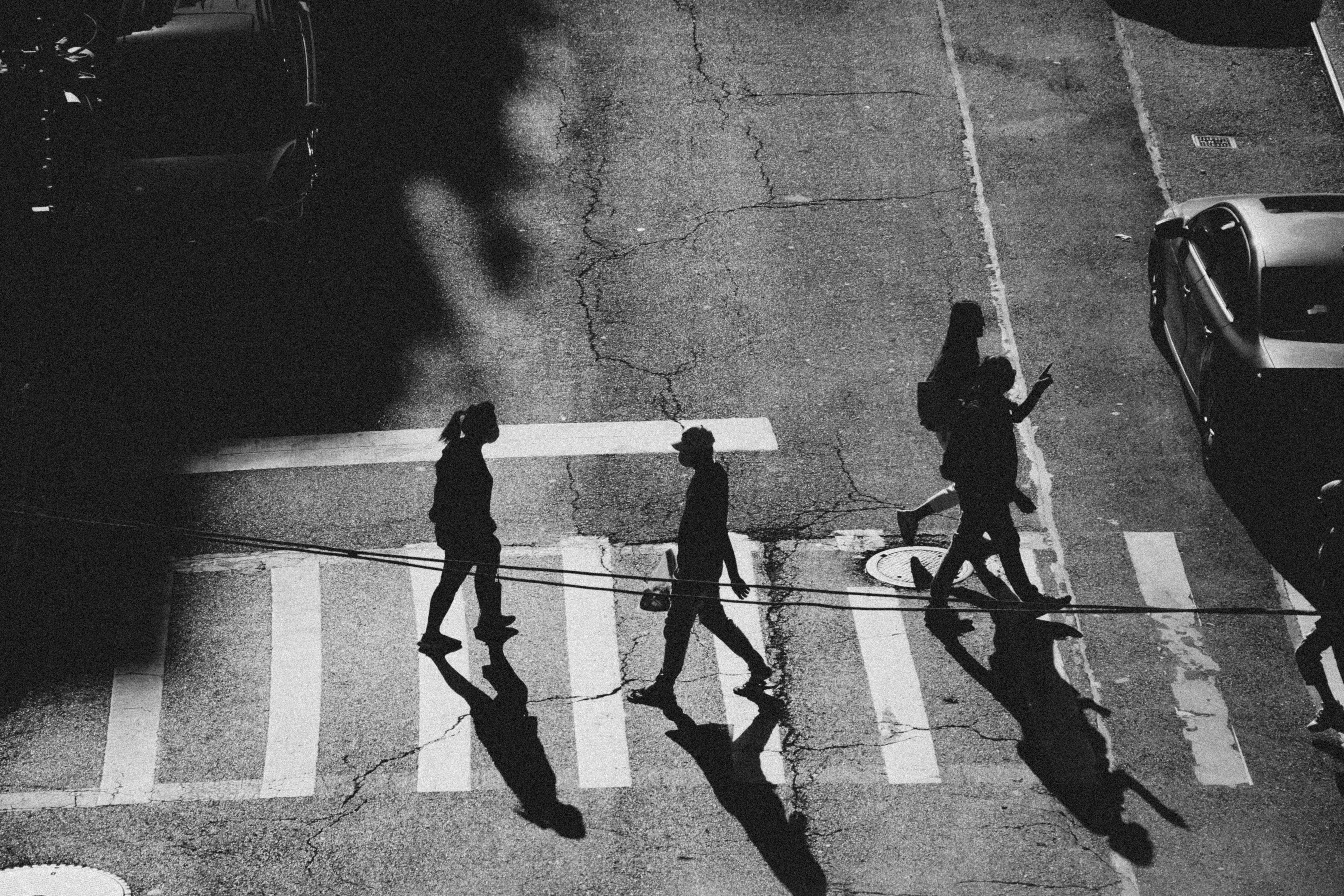 Aerial black and white shot of people crossing a NYC street in dramatic shadows.