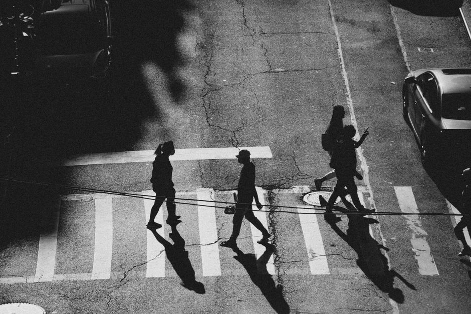 Aerial black and white shot of people crossing a NYC street in dramatic shadows.