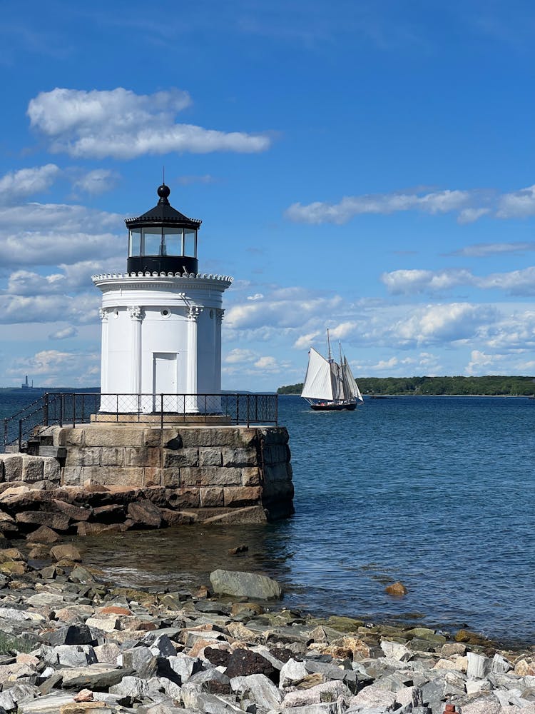 A Boat Sailing Near Bug Light Under Blue Sky