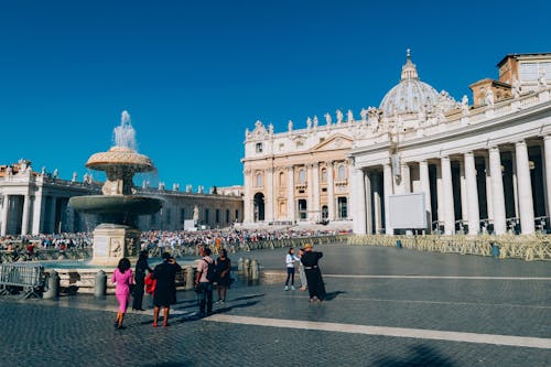 White Building and People Standing Near Water Fountain