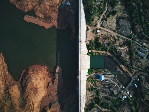 Free Aerial shot of Temghar Dam showcasing the river, rock formations, and lush surroundings. Stock Photo