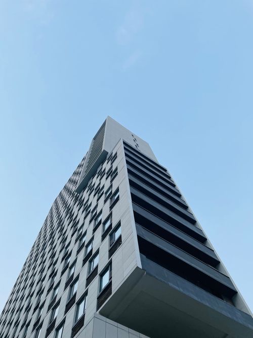 Free Low angle view of a modern skyscraper facade against a clear blue sky, showcasing sleek design. Stock Photo