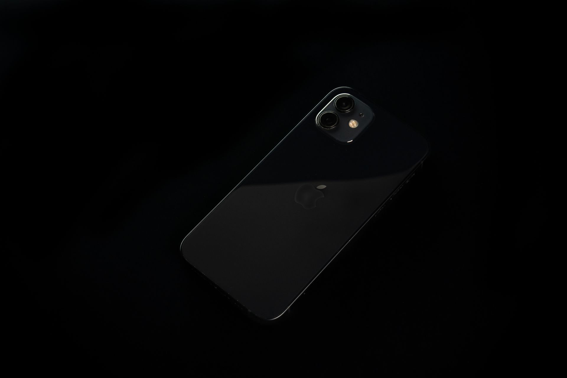 A minimalist close-up of a black smartphone on a dark background, showcasing modern technology.