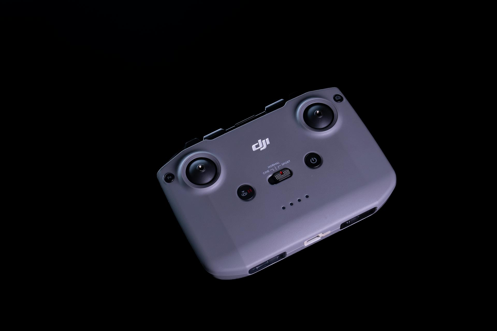 Close-up of a DJI drone controller against a sleek black background.