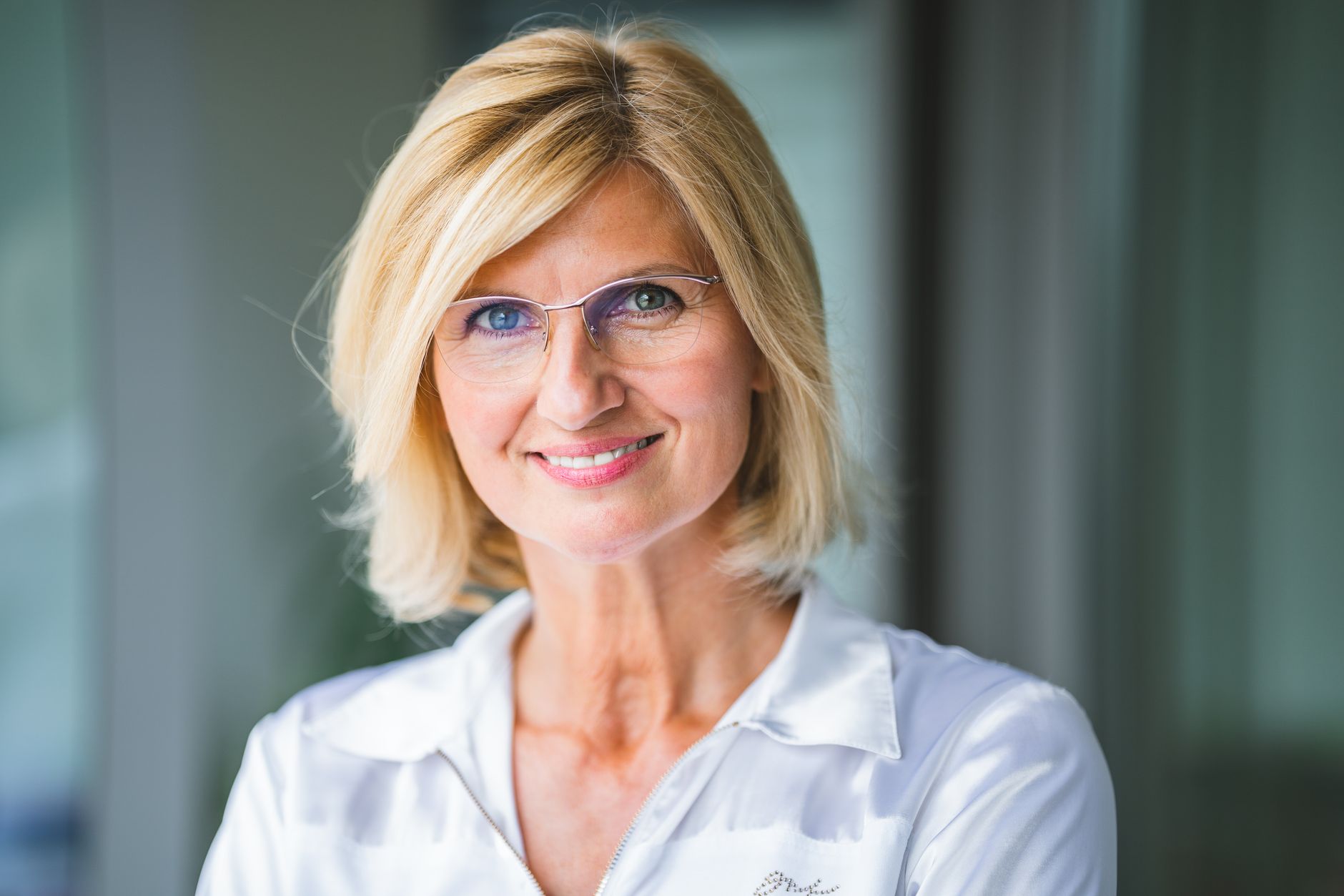 How to Choose Eyeglasses That Reflect Your Personality and Style 4 Close-up of a smiling blonde woman wearing eyeglasses indoors.