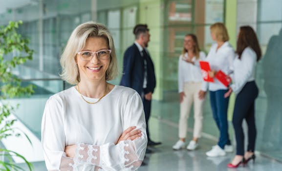 Smiling businesswoman with crossed arms in a bright, modern office environment.