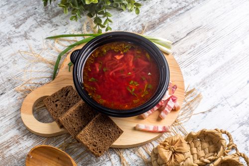 Free Delicious homemade borscht served with rye bread on a wooden tray, enhanced with fresh herbs. Stock Photo