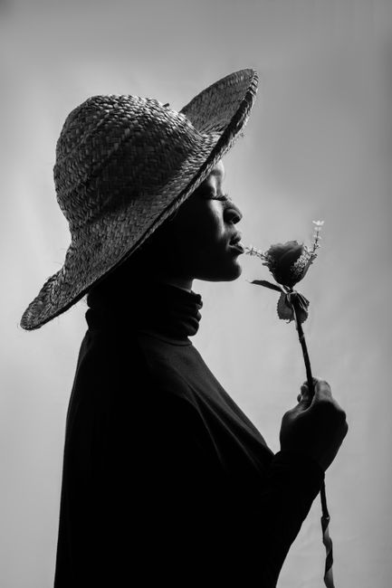 Striking black and white profile of a woman in a straw hat holding a rose.