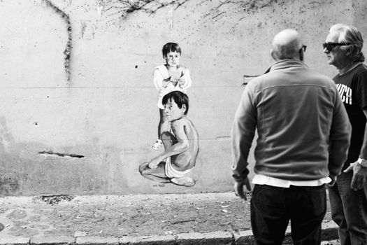 Artistic street scene with mural and people admiring, captured in monochrome.
