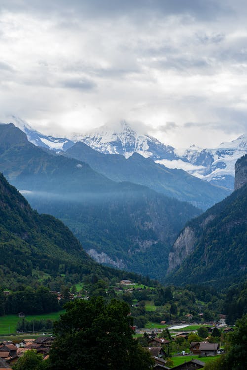 Village in a Valley and Snowcapped Mountains in the Distance 