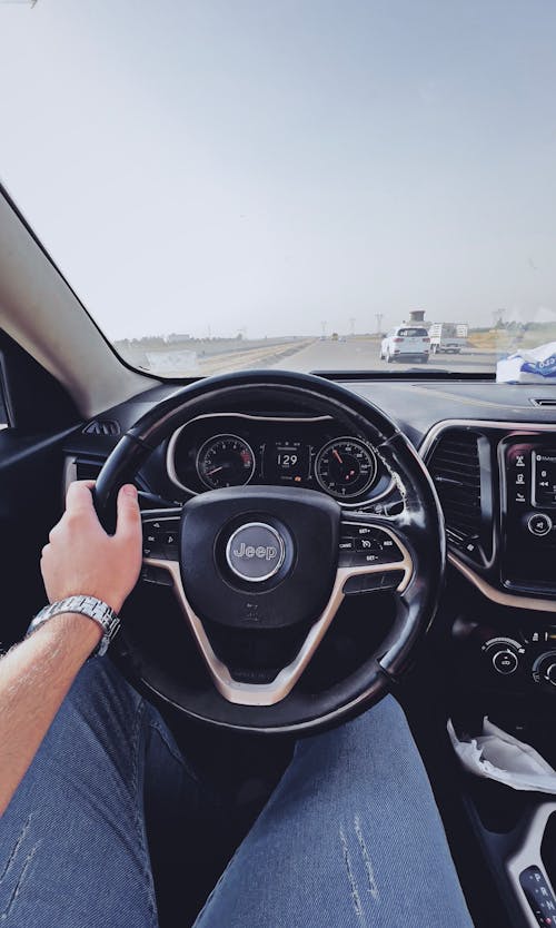 A Person in Denim Pants Controlling the Steering Wheel of a Vehicle