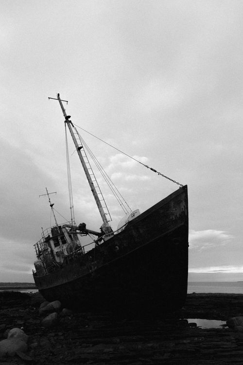 Free Black and white image of a shipwrecked boat on the Murmansk coastline during a cloudy day. Stock Photo