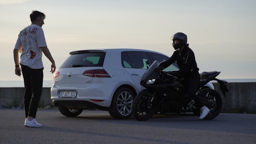 Two Men with a Motorcycle and a White Car