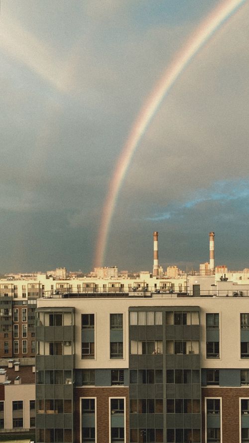 Free Rainbow arcs over city buildings in Russia with clear skies and smokestacks visible. Stock Photo
