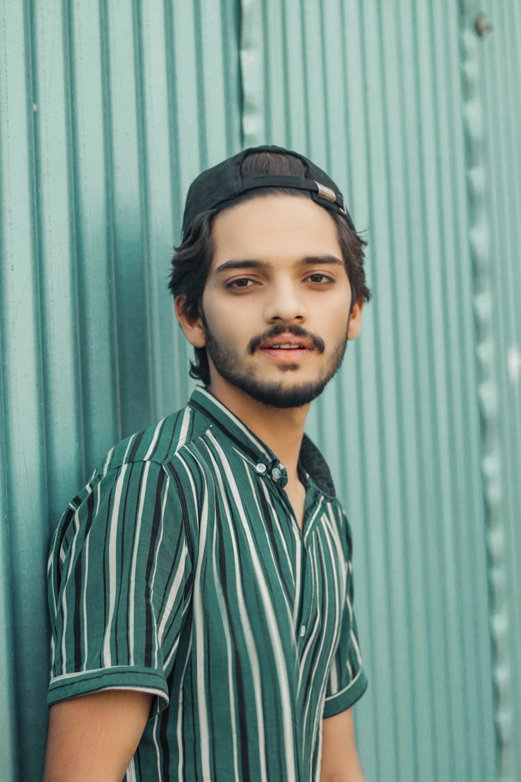 Young Man In Hat Posing Near Wall