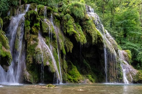 Free Captivating waterfall cascading over moss-covered rocks in a vibrant forest scene. Stock Photo