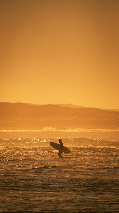 Silhouette of a Surfer on the Ocean during Sunset