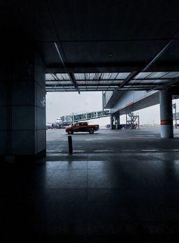 A red pickup truck parked at the terminal entrance of Kolkata Airport, with a clear view of an airplane.