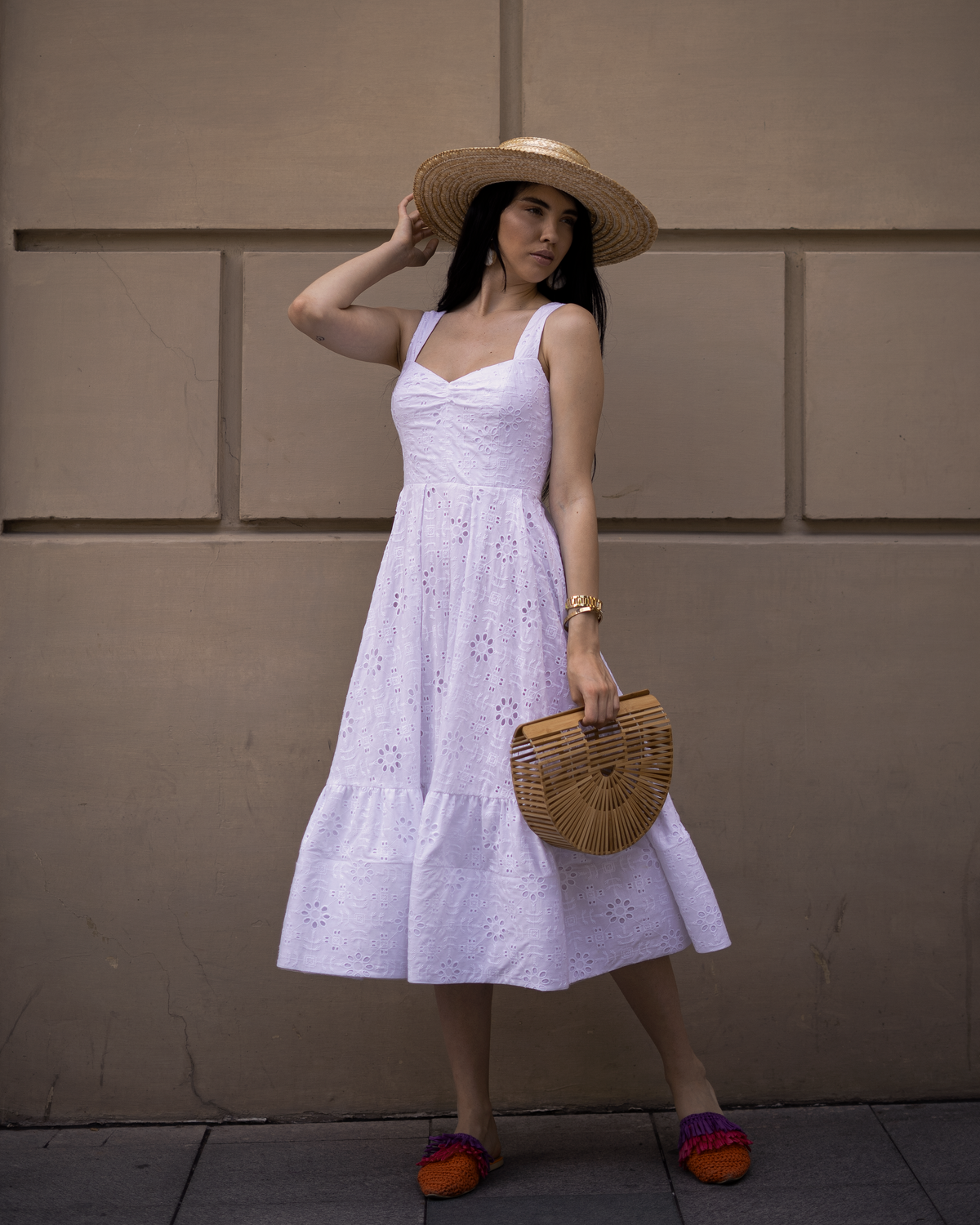 A woman in a white dress holding a bamboo tote bag — broderie styled for summer