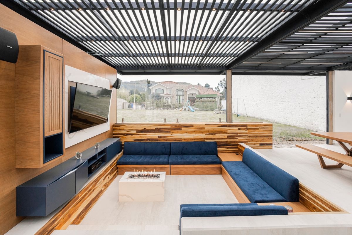 Loungebereich mit Sofa unter einem dunklen Aluminium-Lamellendach