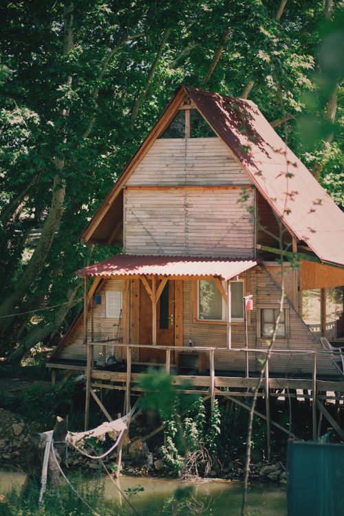 Free Charming wooden A-frame cabin nestled in a verdant forest setting, epitomizing rustic tranquility. Stock Photo