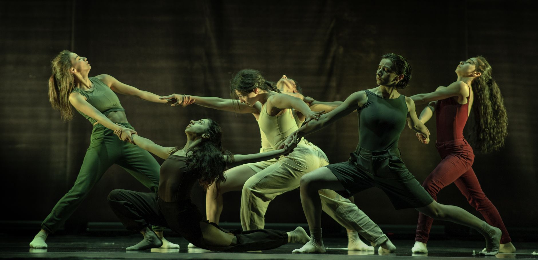 Contemporary dancers performing a dramatic routine with synchronization and movement on stage.
