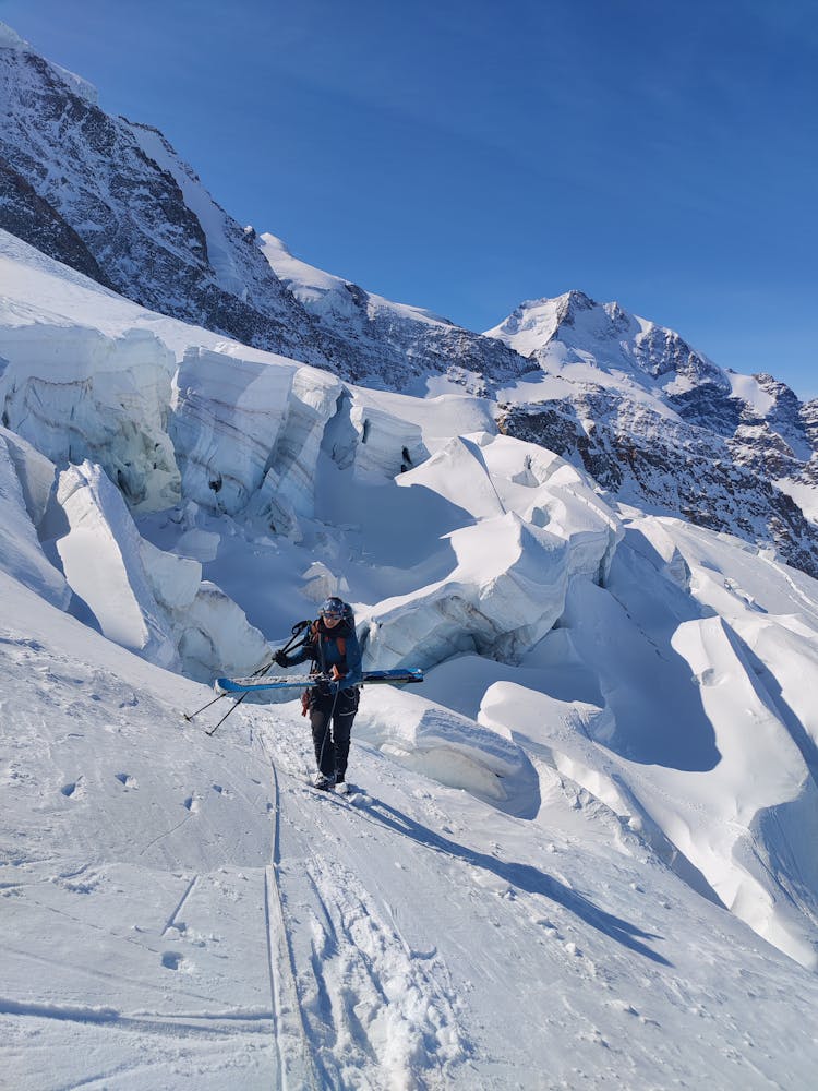 Man With Skis Walking On Snow Covered Mountainside