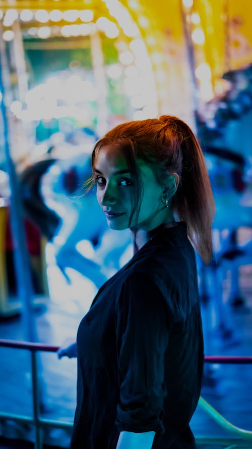 Woman in Black Blouse Standing Beside a Carousel