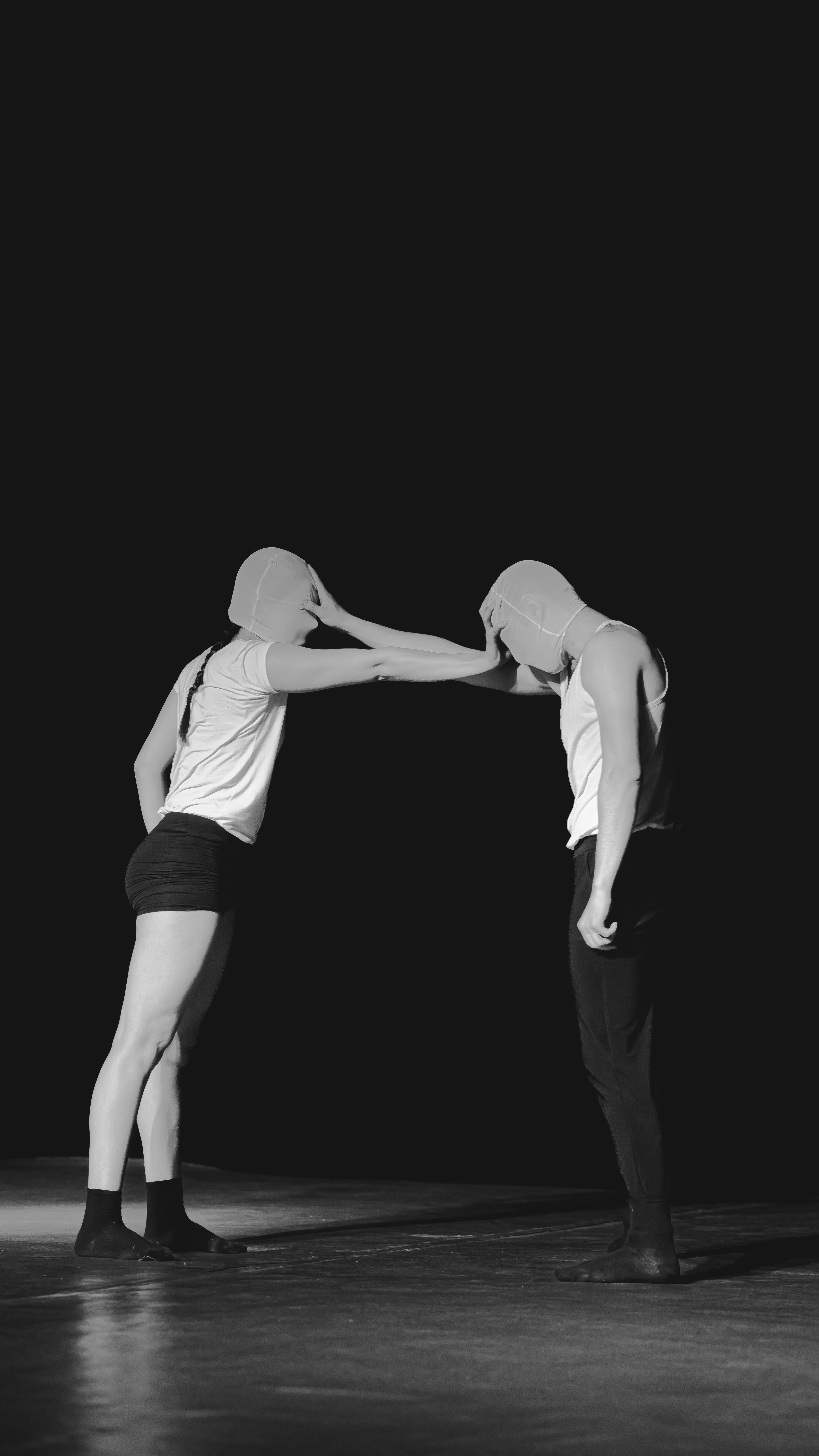 Free Abstract black and white photo of two masked dancers in a dynamic pose on stage. Stock Photo