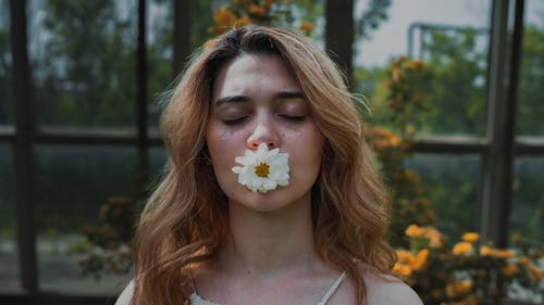 Close-up Shot of a Woman with White Flower on Her Lips