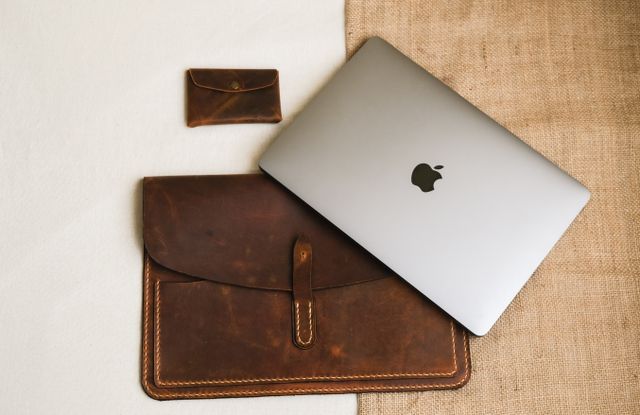 Leather laptop sleeve with a laptop on a neutral cream backdrop
