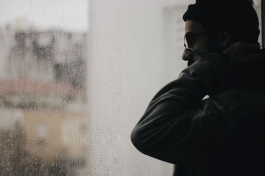 Man standing by the window in a rainy day