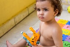 Cute toddler focused on playing with colorful plastic toys indoors on a sunny day.